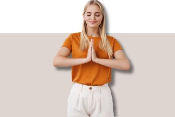 mulher loira com uma camiseta laranja com os olhos fechados e as palmas das mãos juntas em posição de meditação mindfulness atenção plena para reduzir estresse e ansiedade